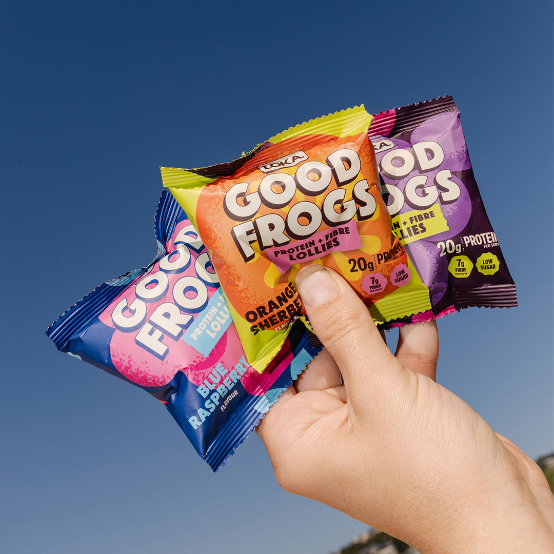 image of hand with a mix of protein lolly flavours packages with a deep blue sky in background